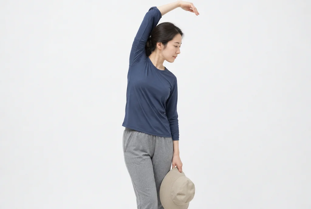 흰 스튜디오 안에서 운동복 차림 30대 여성이 챙 모자를 손에 들고 스트레칭하는 반신 옆모습